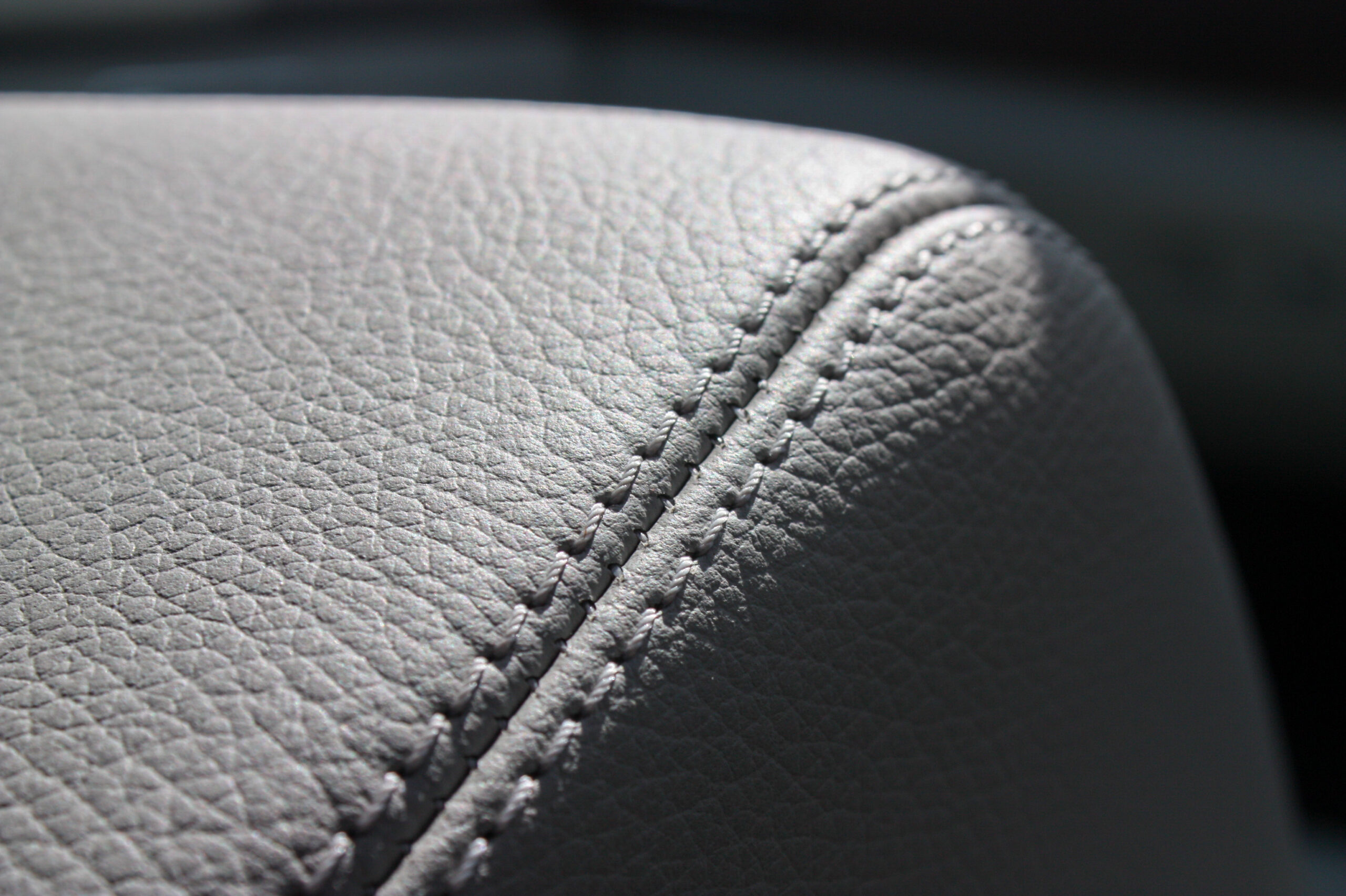 Close-up of gray textured leather upholstery with detailed stitching.