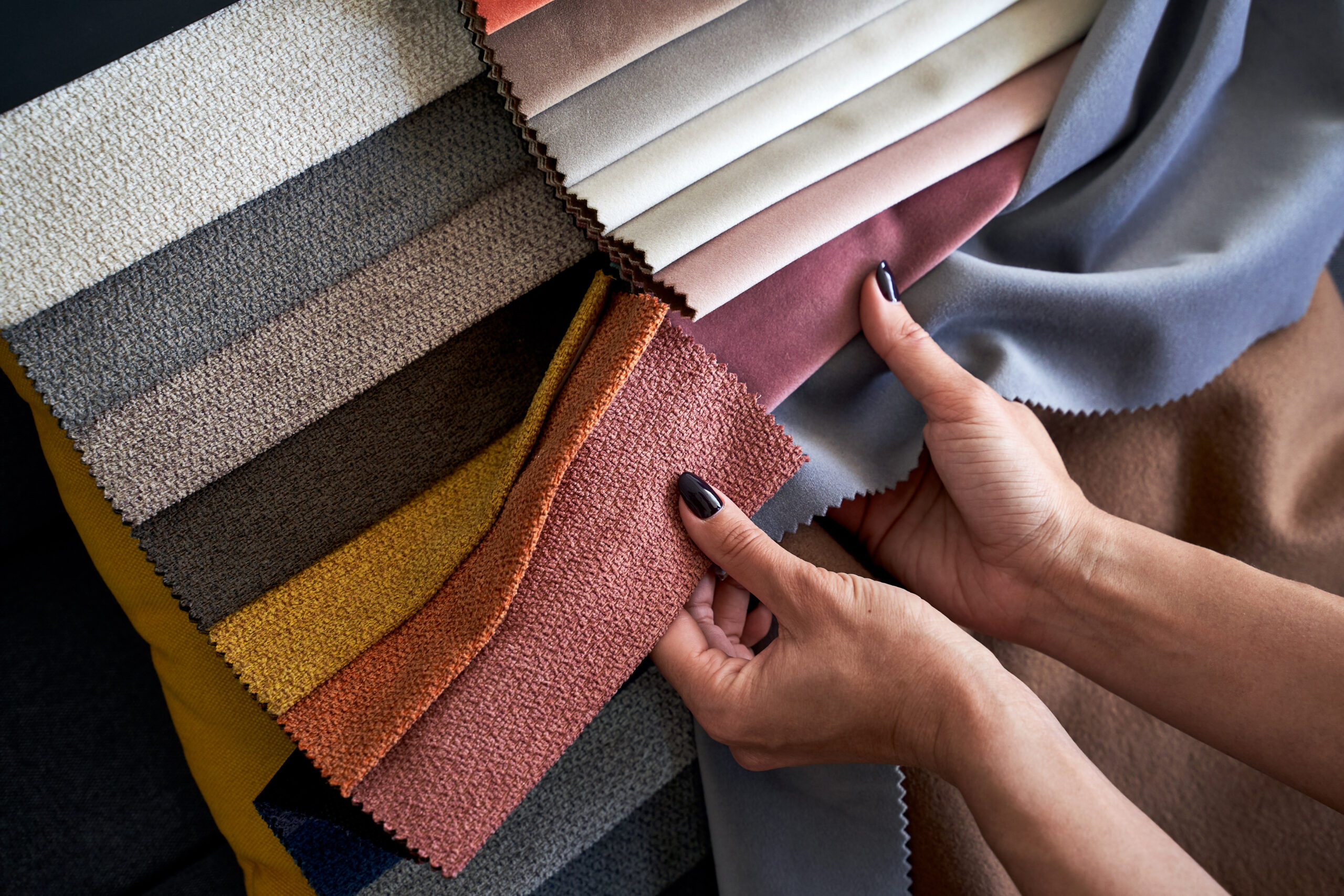 Person selecting colorful fabric samples for upholstery or design projects.